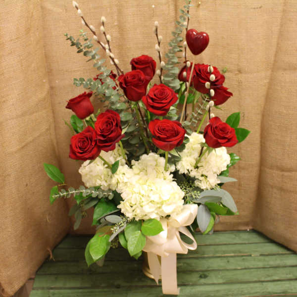 Red roses and white hydrangeas in a tall arrangement with a ribbon bow
