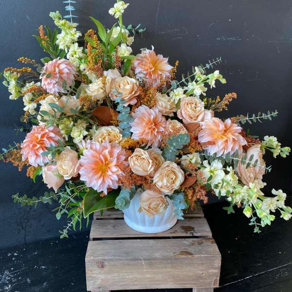 Large peach and cream floral arrangement in a white vase