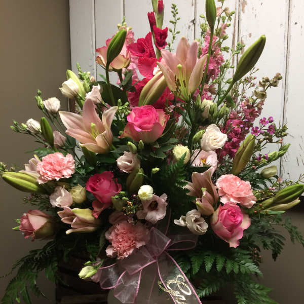 Pink and white floral arrangement in a white vase with a ribbon bow