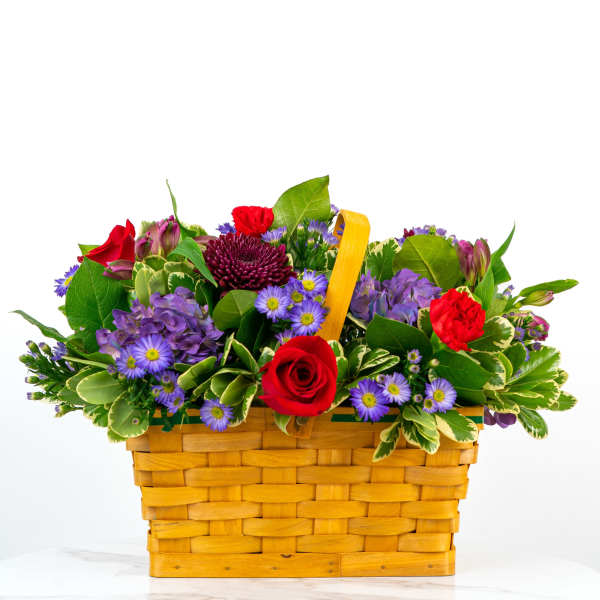 Mixed bouquet in a woven basket with red and purple flowers