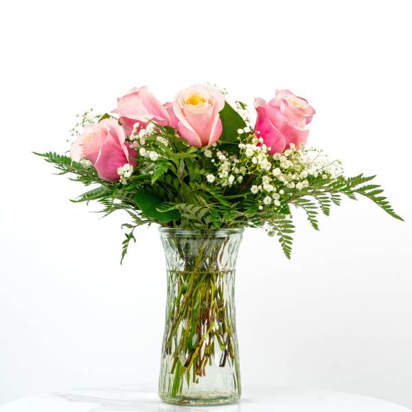 Pink roses with white filler flowers in a clear glass vase