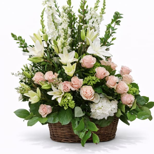 Basket arrangement of pink roses and white lilies with tall white blooms
