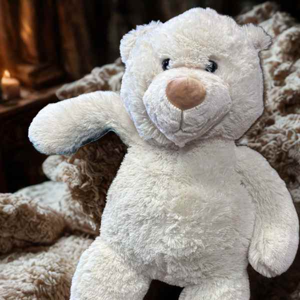 White plush teddy bear sitting on a brown patterned blanket