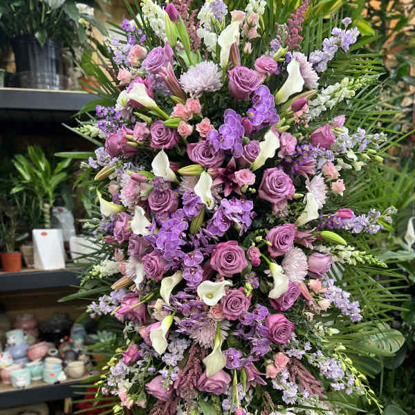 Large standing floral spray with purple roses, white calla lilies, and orchids