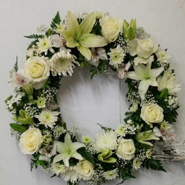 White floral wreath with roses, lilies, and daisies