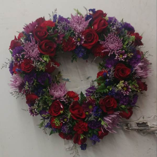 Heart-shaped floral wreath with red roses and purple flowers