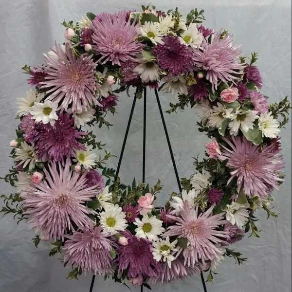 Lavender and white floral wreath on a black stand