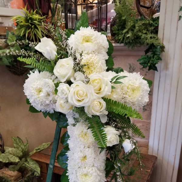 White roses and chrysanthemums arranged in a cross-shaped standing spray