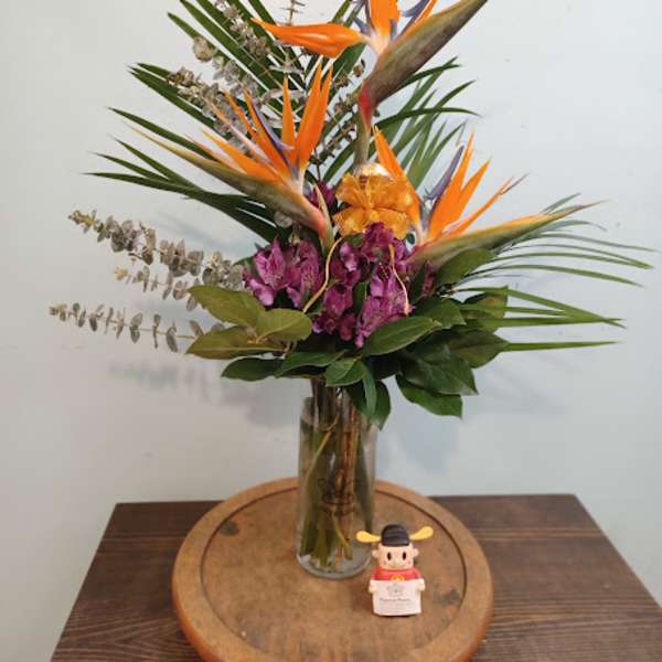 Tropical flower arrangement with orange bird-of-paradise in a glass vase