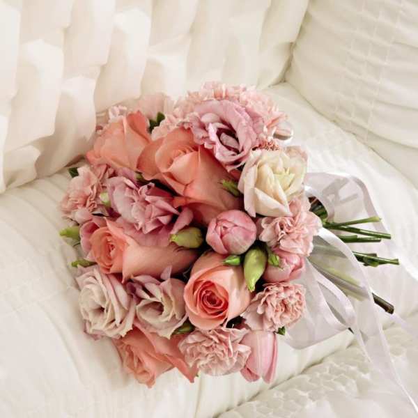 Pink and peach bouquet of roses and carnations with a white ribbon