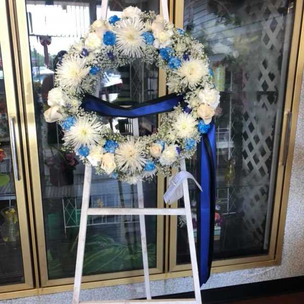 White and blue floral wreath on a standing easel with ribbon