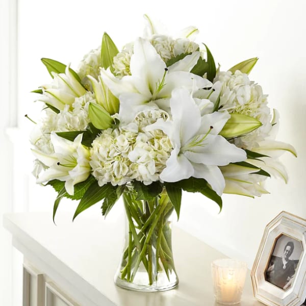 White lilies and hydrangeas in a clear glass vase