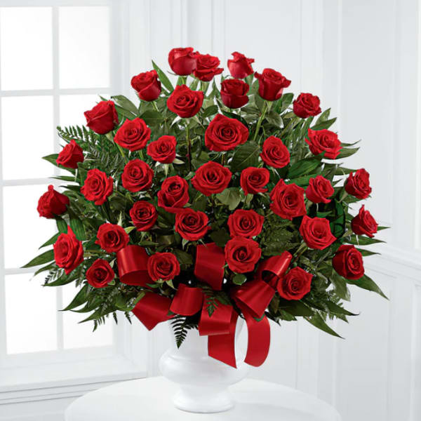 Large bouquet of red roses in a white vase with a red ribbon