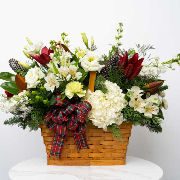 Holiday flower basket with white blooms, red lilies, and a plaid ribbon