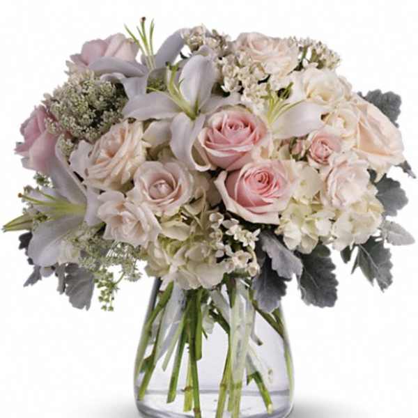 Blush roses and white lilies in a clear glass vase