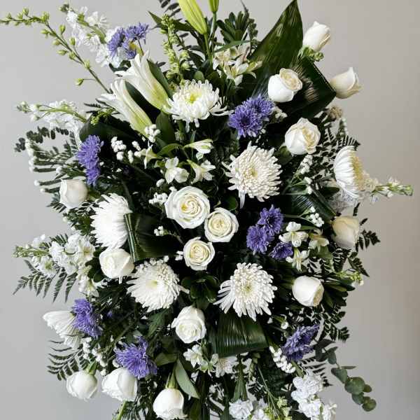 White and purple funeral spray with roses, lilies, and chrysanthemums
