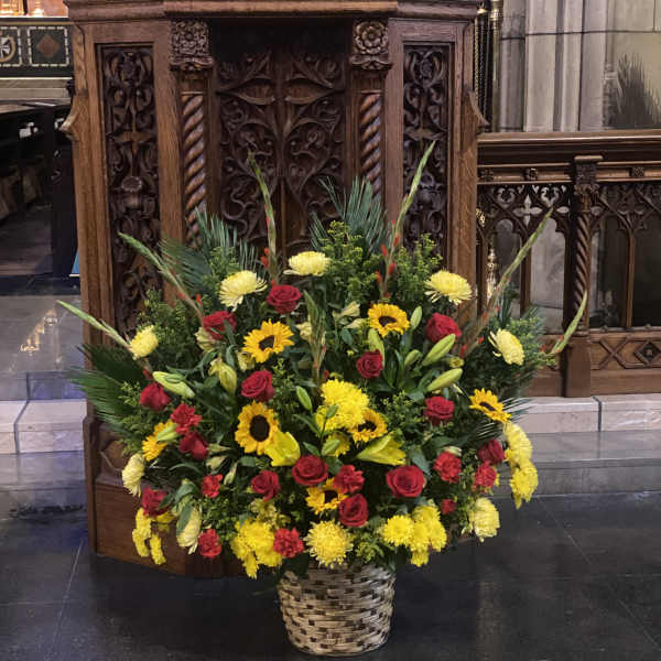 Large basket arrangement of red roses, yellow sunflowers, and lilies