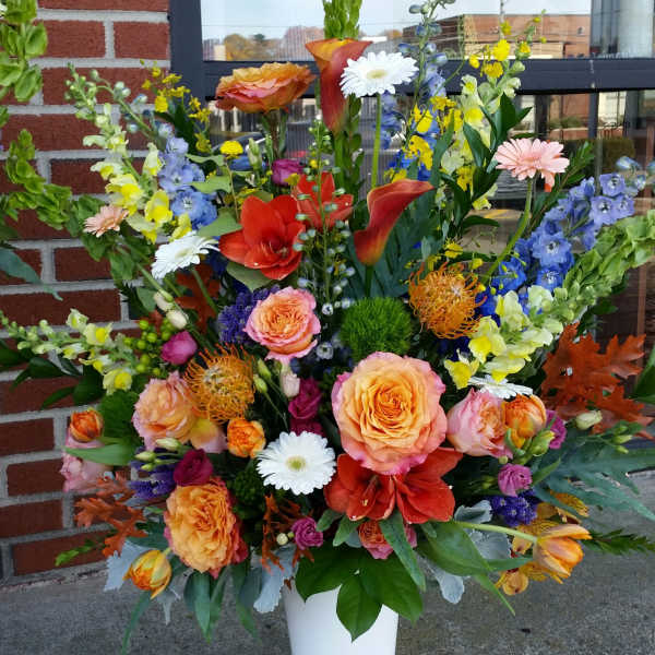 Large mixed flower arrangement in a white pedestal vase
