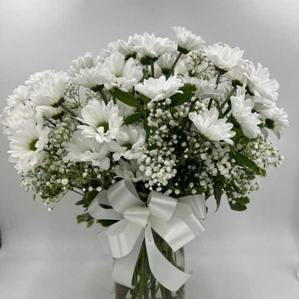 White daisy bouquet in a glass vase with a white ribbon