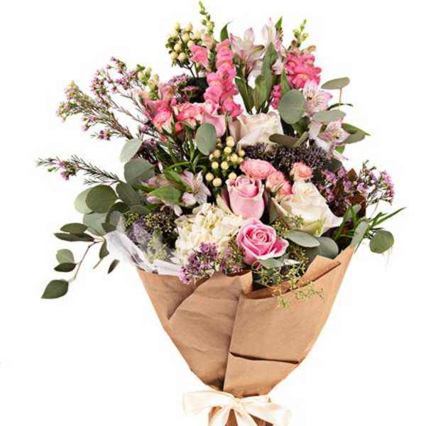 Bouquet of pink and white flowers wrapped in brown paper with a ribbon