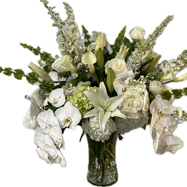 White floral arrangement in a glass vase with orchids, roses, and lilies