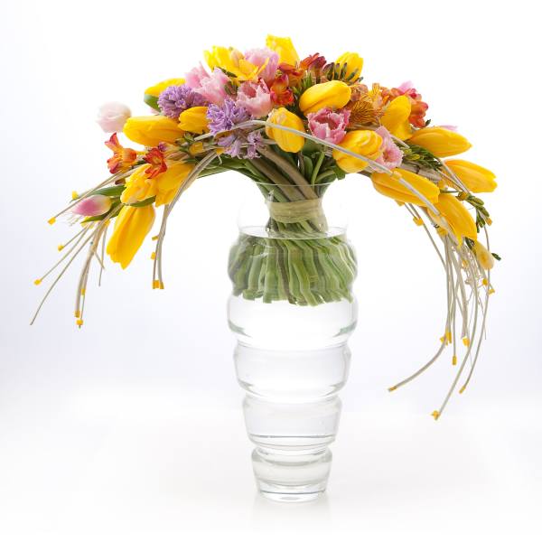 Bouquet of yellow, pink, and purple flowers in a clear glass vase