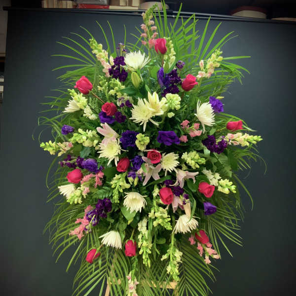 Large standing floral spray with pink roses, white blooms, and purple flowers