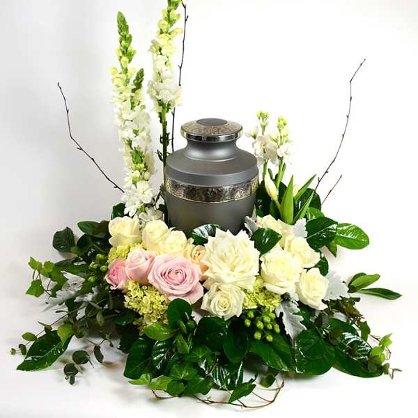 Floral urn arrangement with roses and white blooms around a gray memorial urn