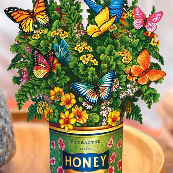 Butterfly-themed floral arrangement in a honey can container