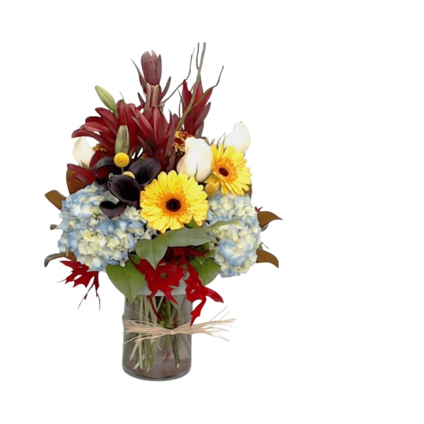 Bouquet of yellow gerbera daisies, blue hydrangeas, and red tropical flowers in a glass vase