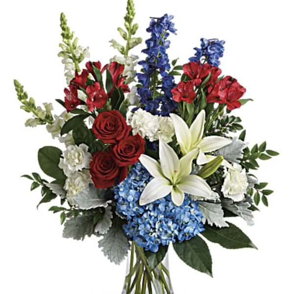 Mixed bouquet of red roses, white lilies, blue flowers, and hydrangeas in a glass vase