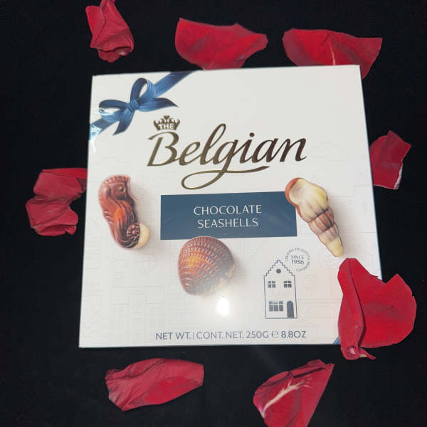 Box of Belgian chocolate seashells surrounded by red petals