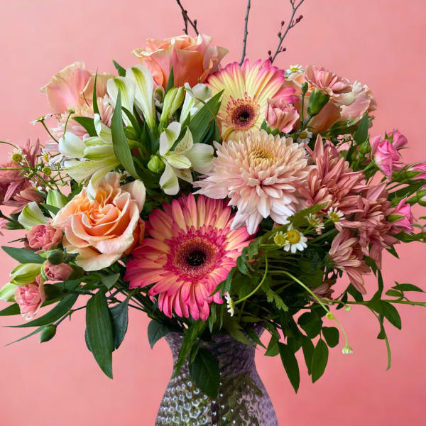 Mixed pink and peach bouquet in a textured glass vase