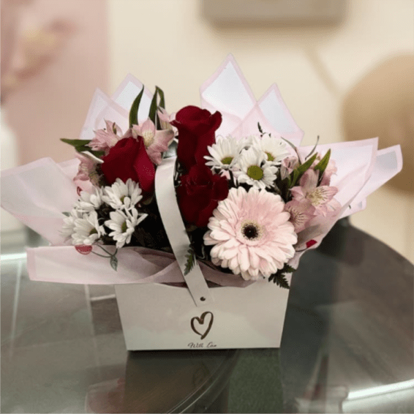 Bouquet of red roses, pink gerbera daisies, and white daisies in a gift box