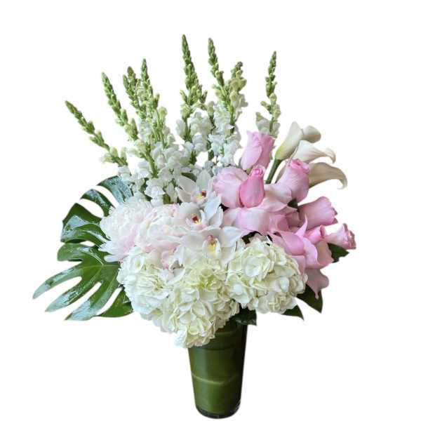 Tall arrangement of white hydrangeas, orchids, snapdragons and pink roses in a glass vase