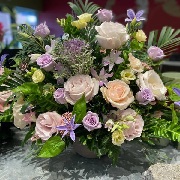 Mixed pastel bouquet with roses and purple star-shaped flowers in a vase