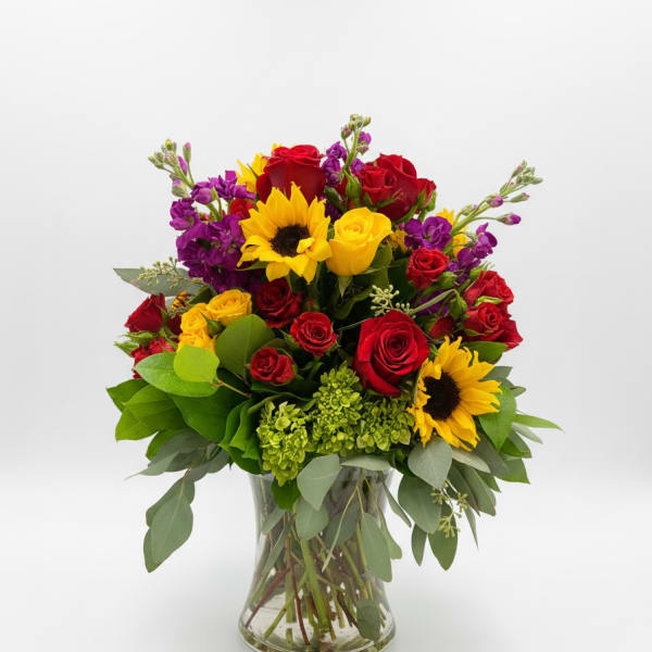 Bouquet of red and yellow roses with sunflowers in a glass vase