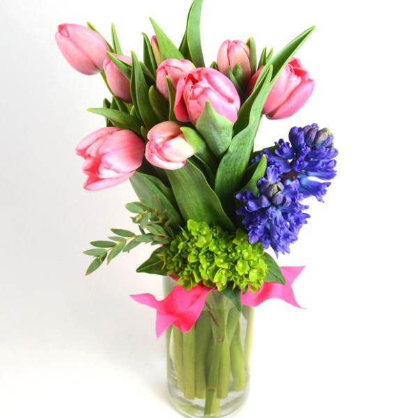 Pink tulips and purple hyacinths in a clear glass vase