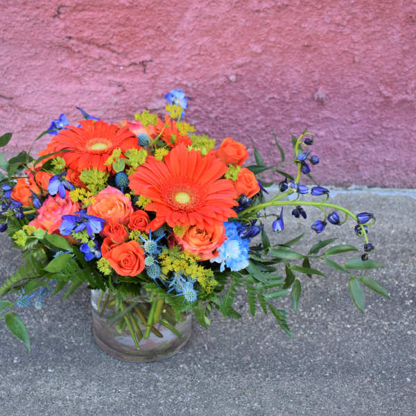Bright mixed bouquet in a glass vase with orange and blue flowers