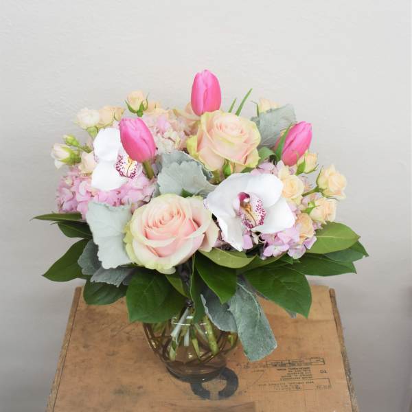 Pink and cream bouquet with roses, tulips, orchids, and hydrangea in a glass vase