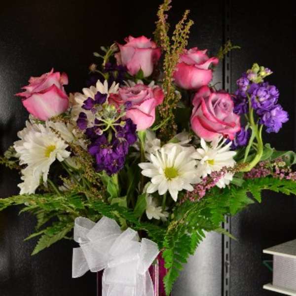 Pink roses and white daisies in a red vase with a white bow