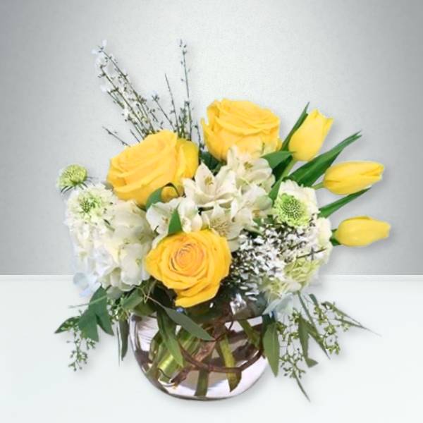 Yellow roses and white flowers in a glass vase