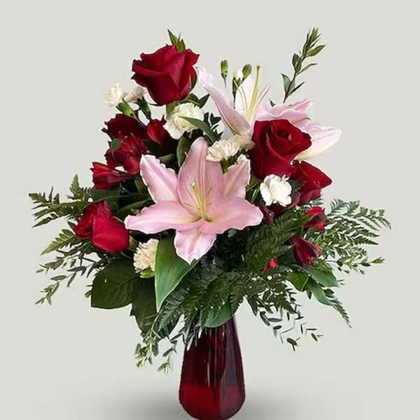 Red roses and pink lilies in a red glass vase