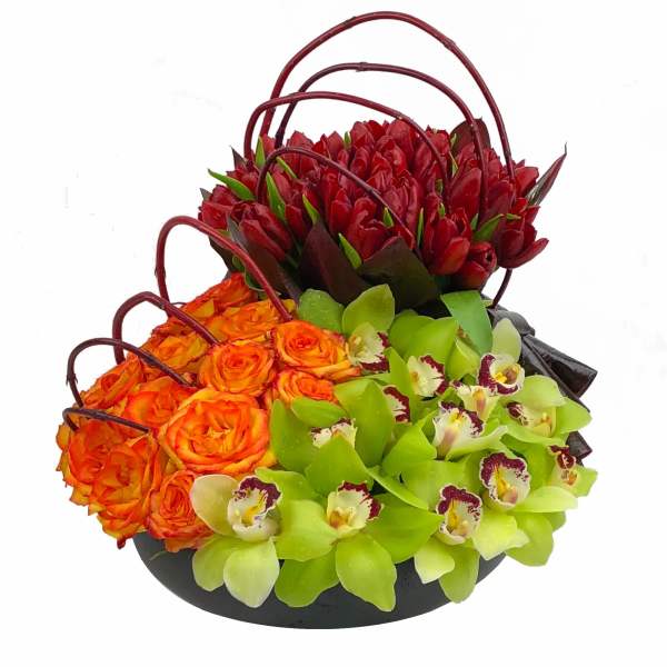 Basket arrangement of red tulips, orange roses, and green orchids