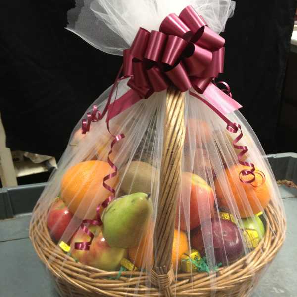 Fruit basket wrapped in white tulle with a burgundy bow