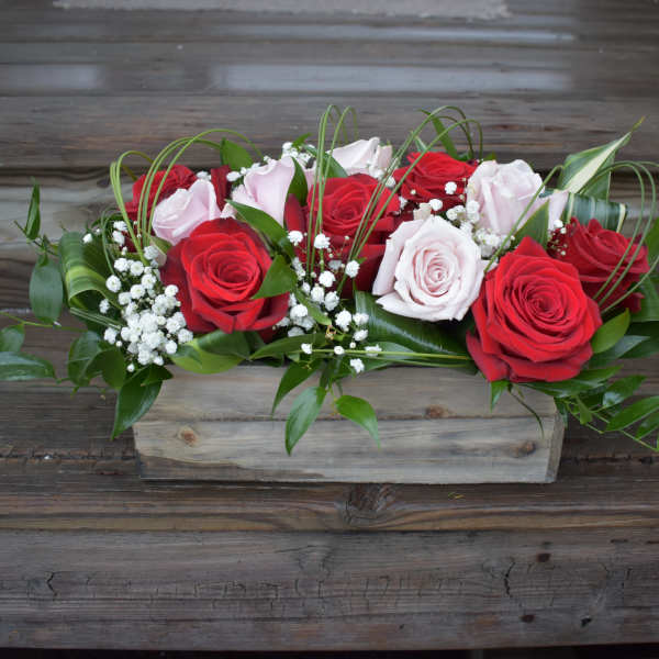 Red and pale pink roses arranged in a wooden box