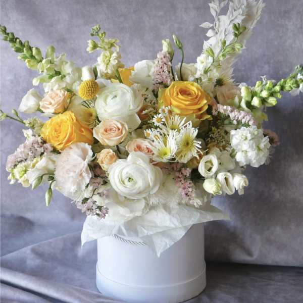 Mixed bouquet of yellow and white flowers in a white hat box