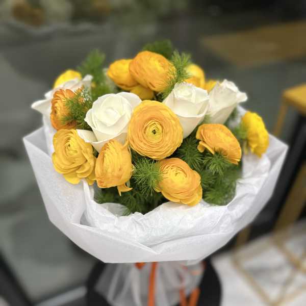Bouquet of yellow and white ranunculus wrapped in white paper