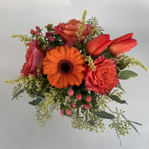 Bouquet of orange gerbera daisies, coral roses, and red tulips