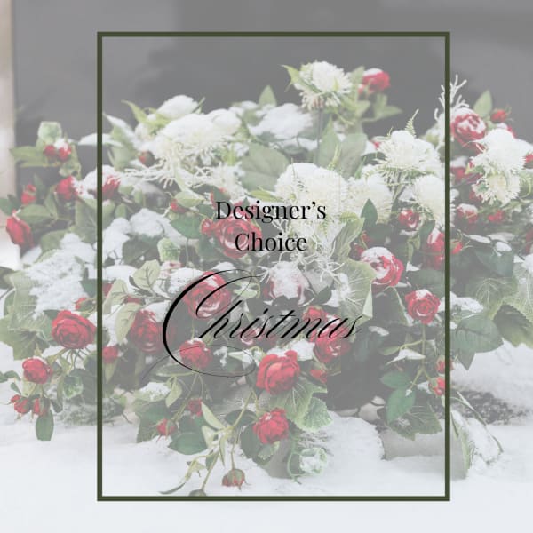 Snow-dusted arrangement of red roses and white flowers in a lush, low Christmas display